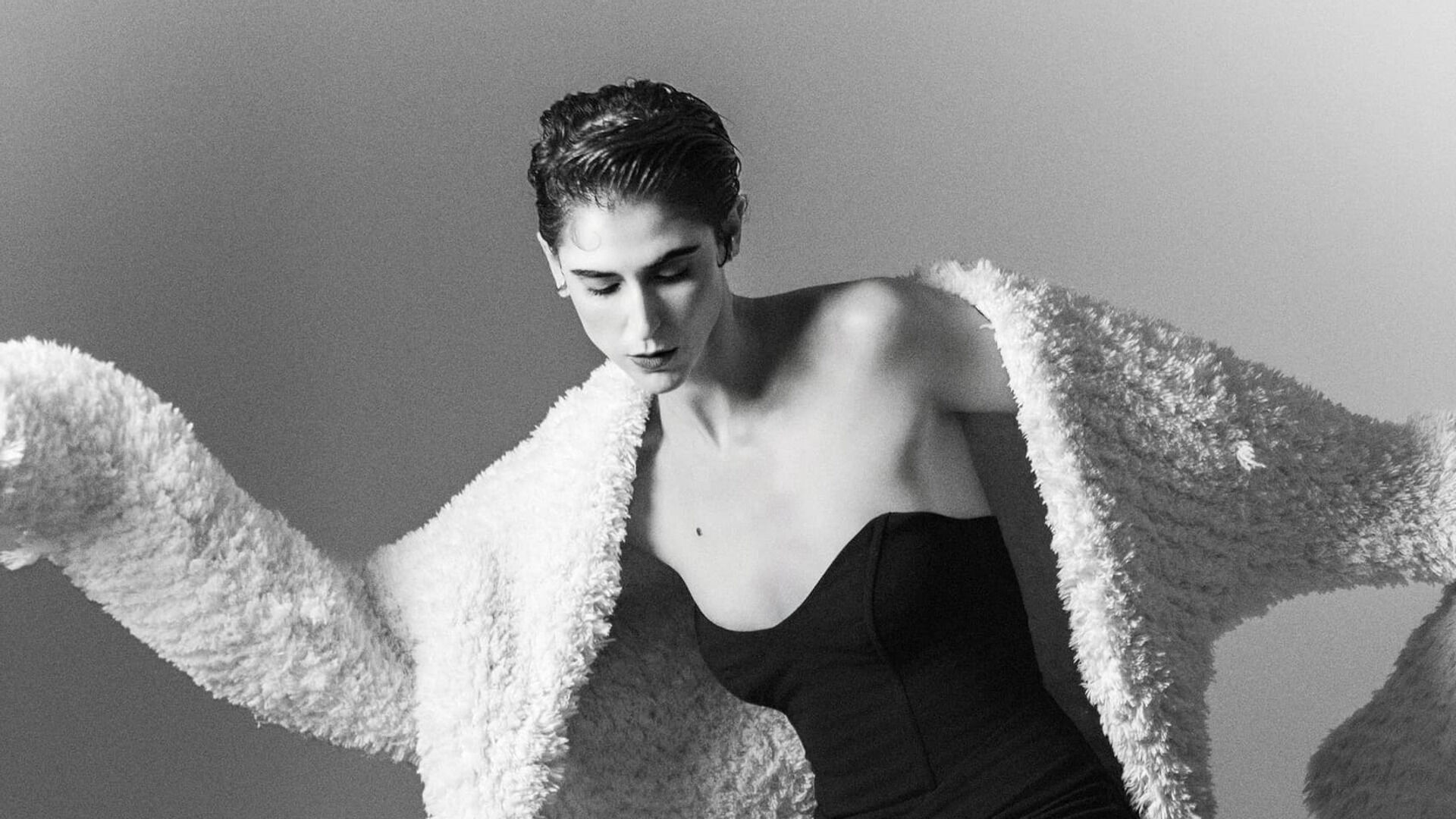 Daiane Conterato in a textured light coat over a dark Dot dress, photographed by Talles.
