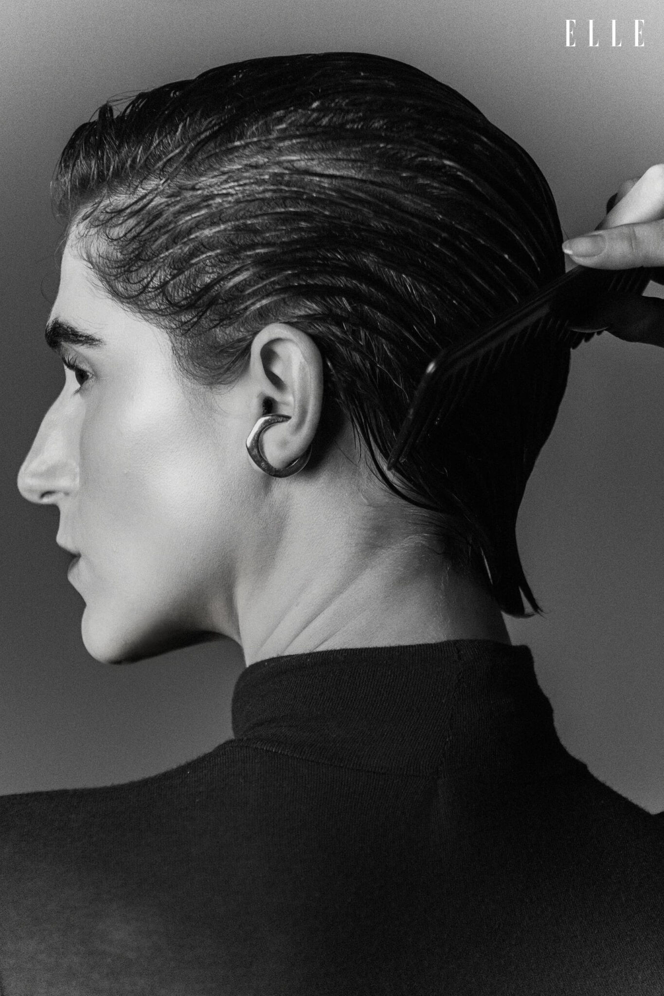 Side portrait of Daiane Conterato with slicked-back hair and an earring.
