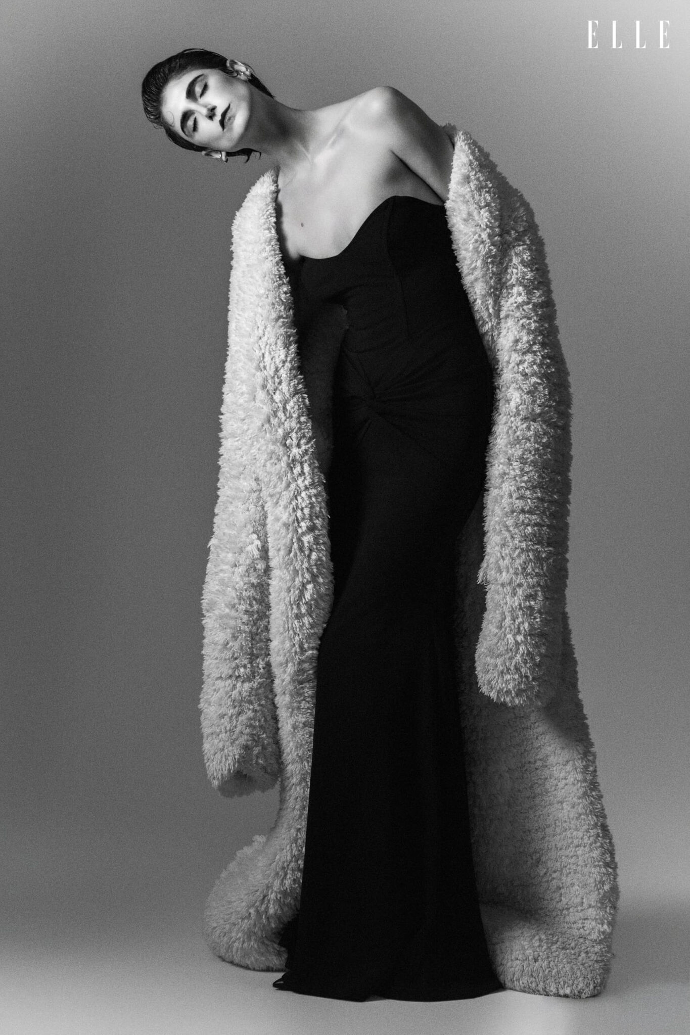 Daiane Conterato wearing a textured light coat over a dark dress.