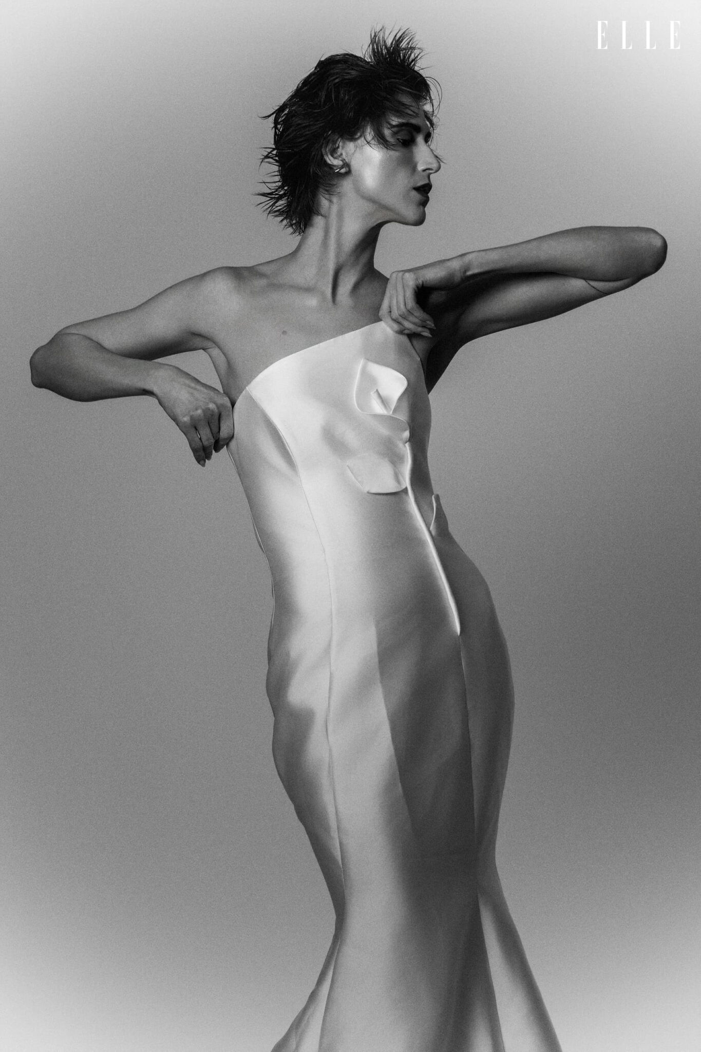 Daiane Conterato in a light strapless dress, with her arms raised.