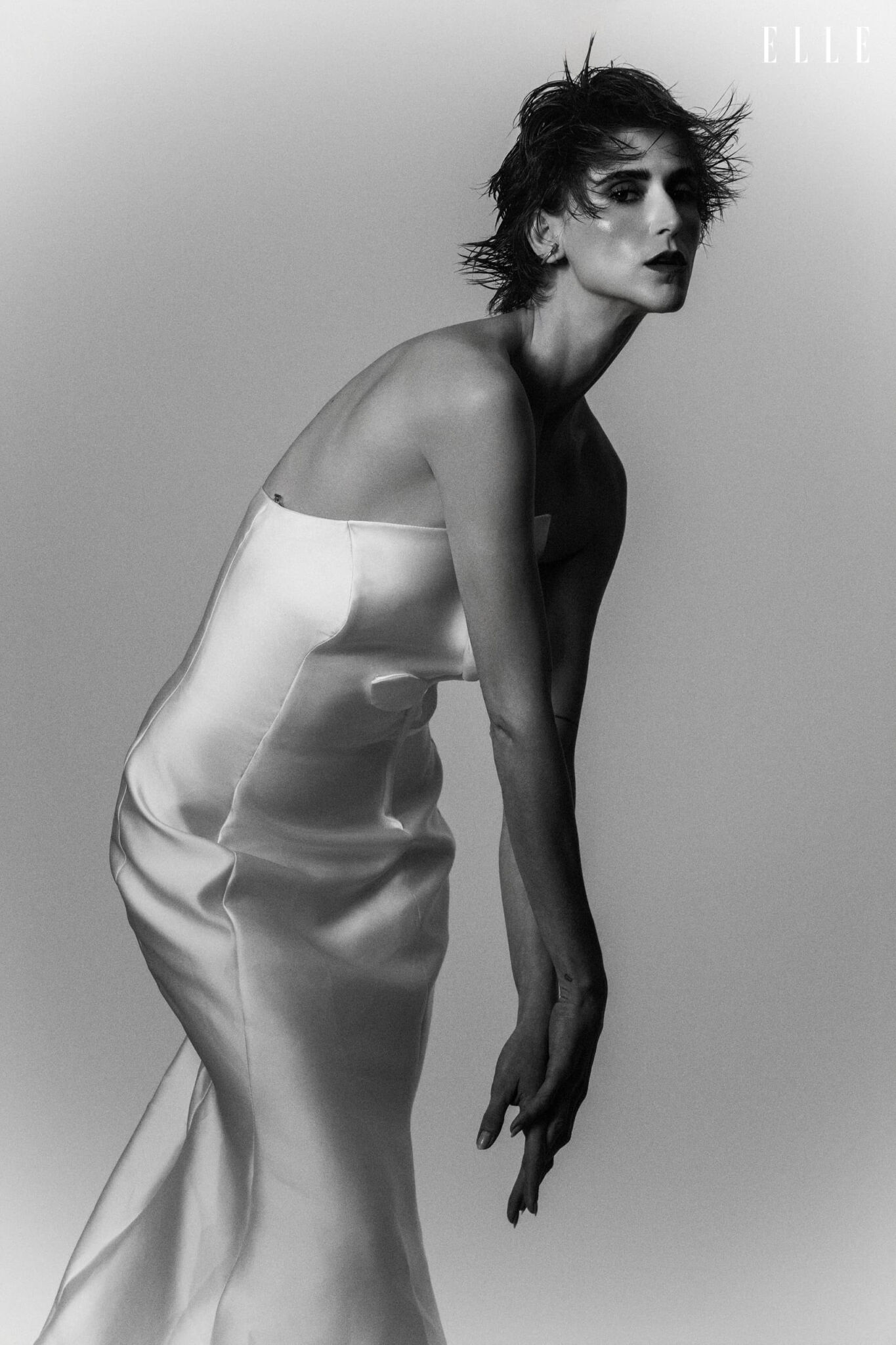 Daiane Conterato leaning forward in a light strapless dress.