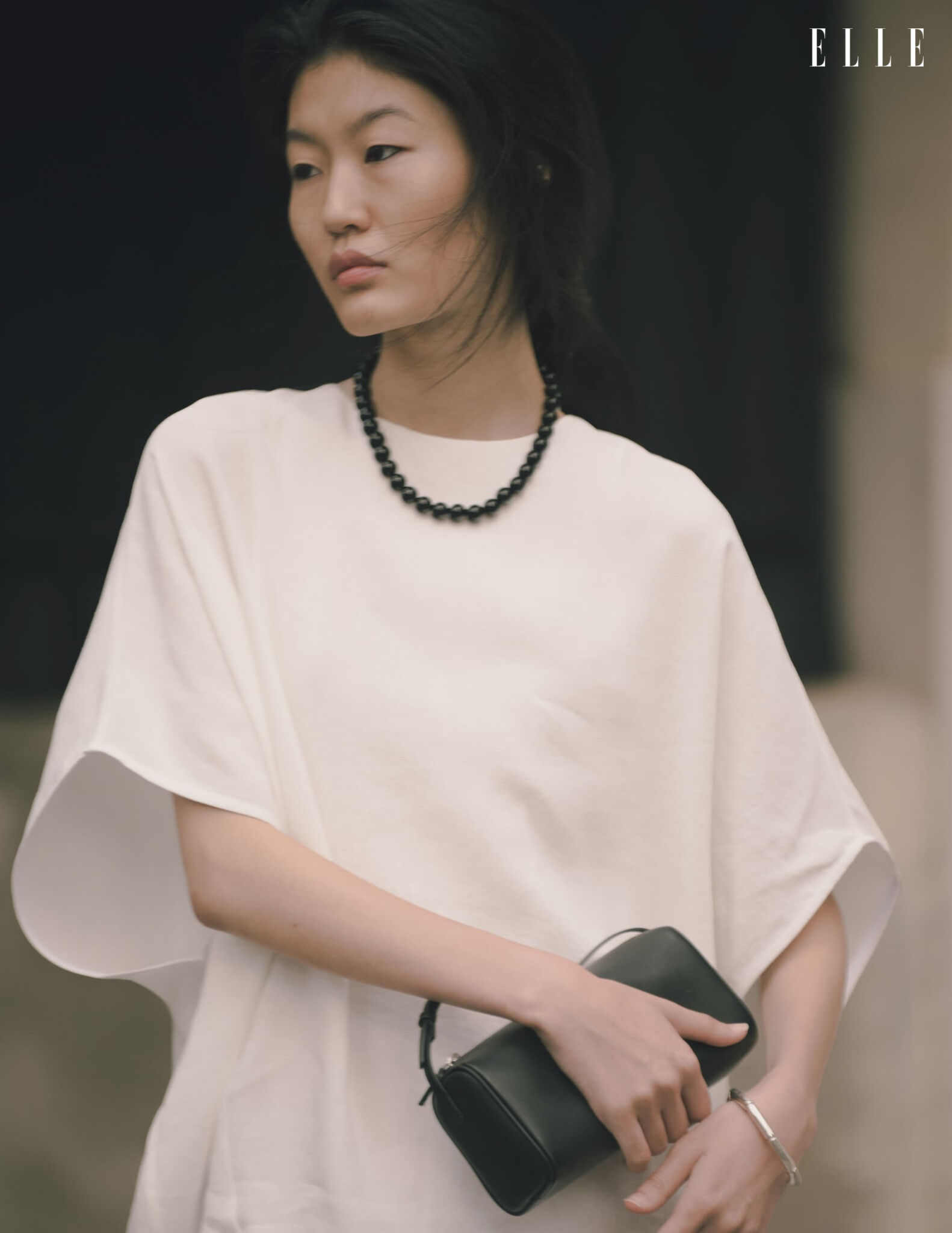 Qian Wen Wu in a white dress with a black bag and necklace
