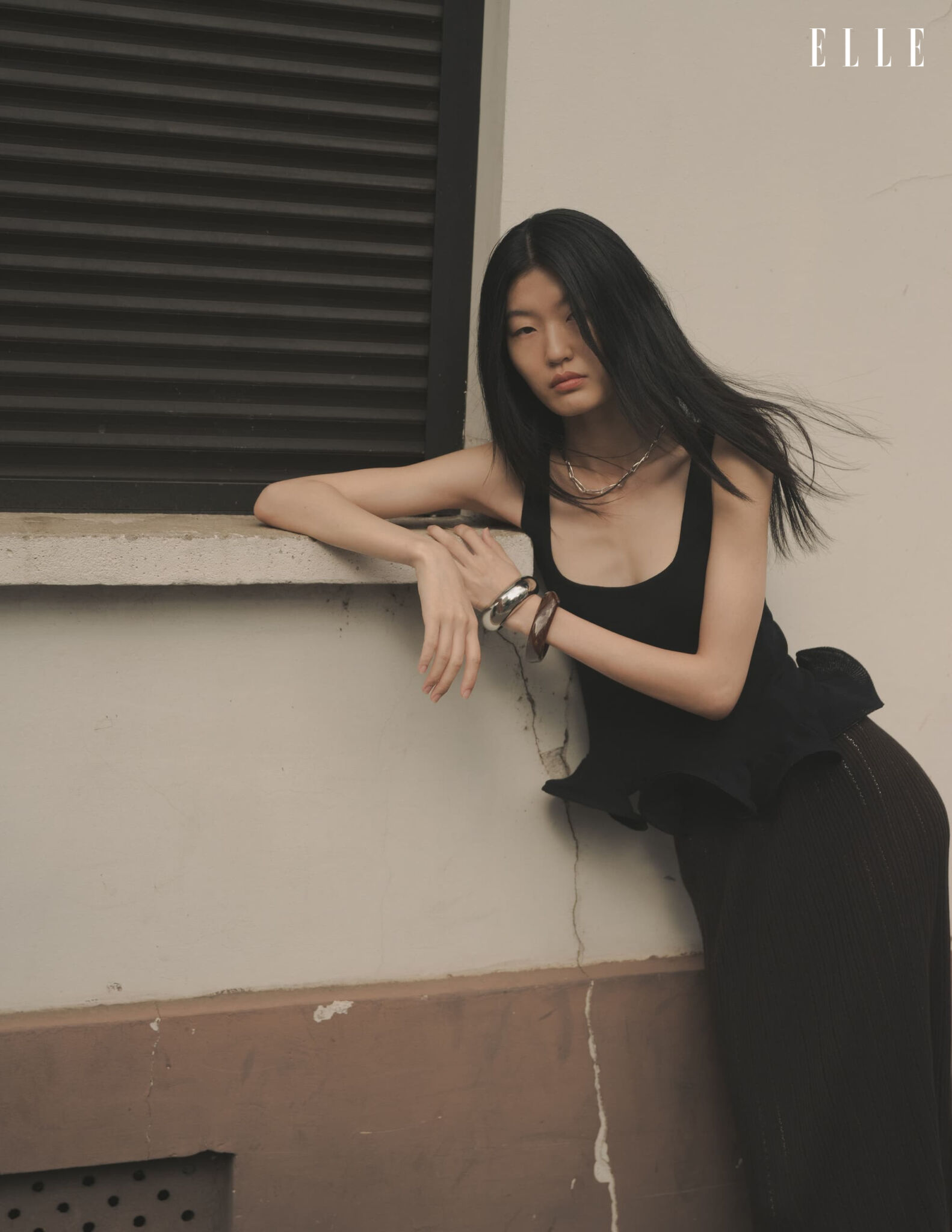 Qian Wen Wu in a black top leaning on a windowsill