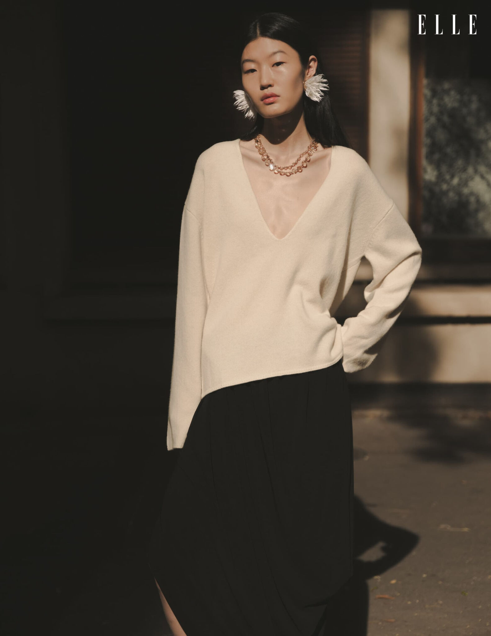 Cream sweater and black skirt in dappled sunlight