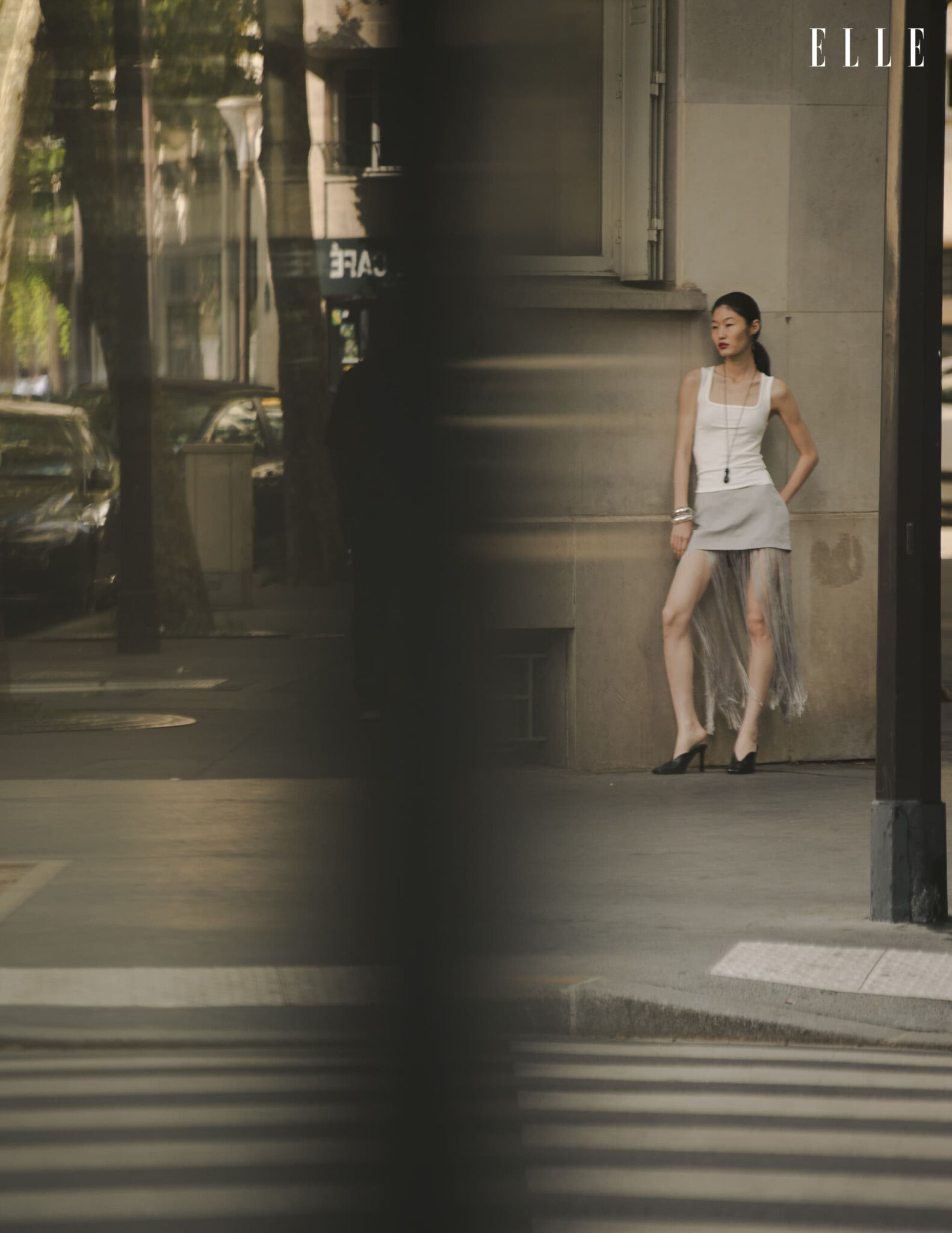 Qian Wen Wu in a pale top and skirt beside a pedestrian crossing
