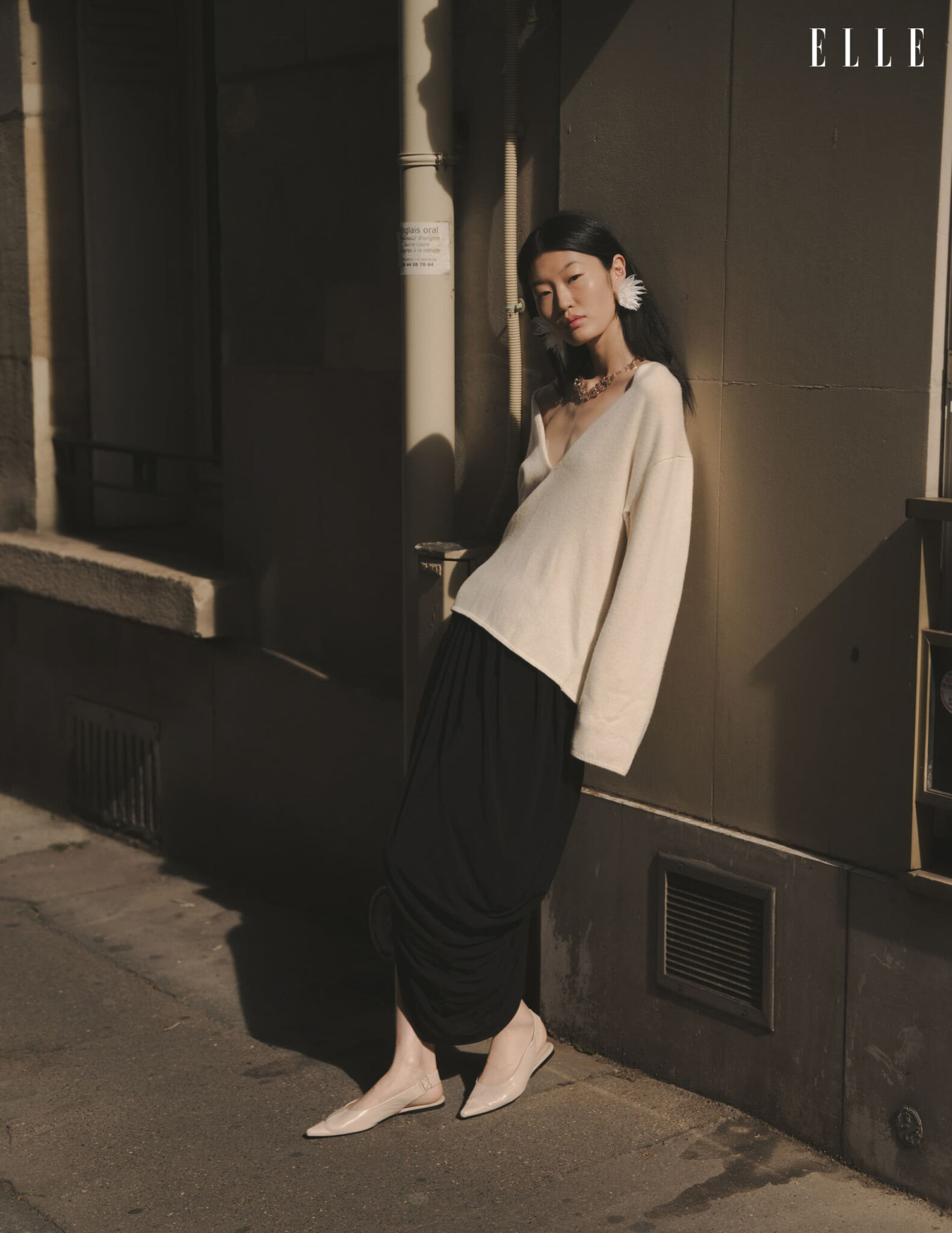 Qian Wen Wu in soft knitwear beside a Paris doorway