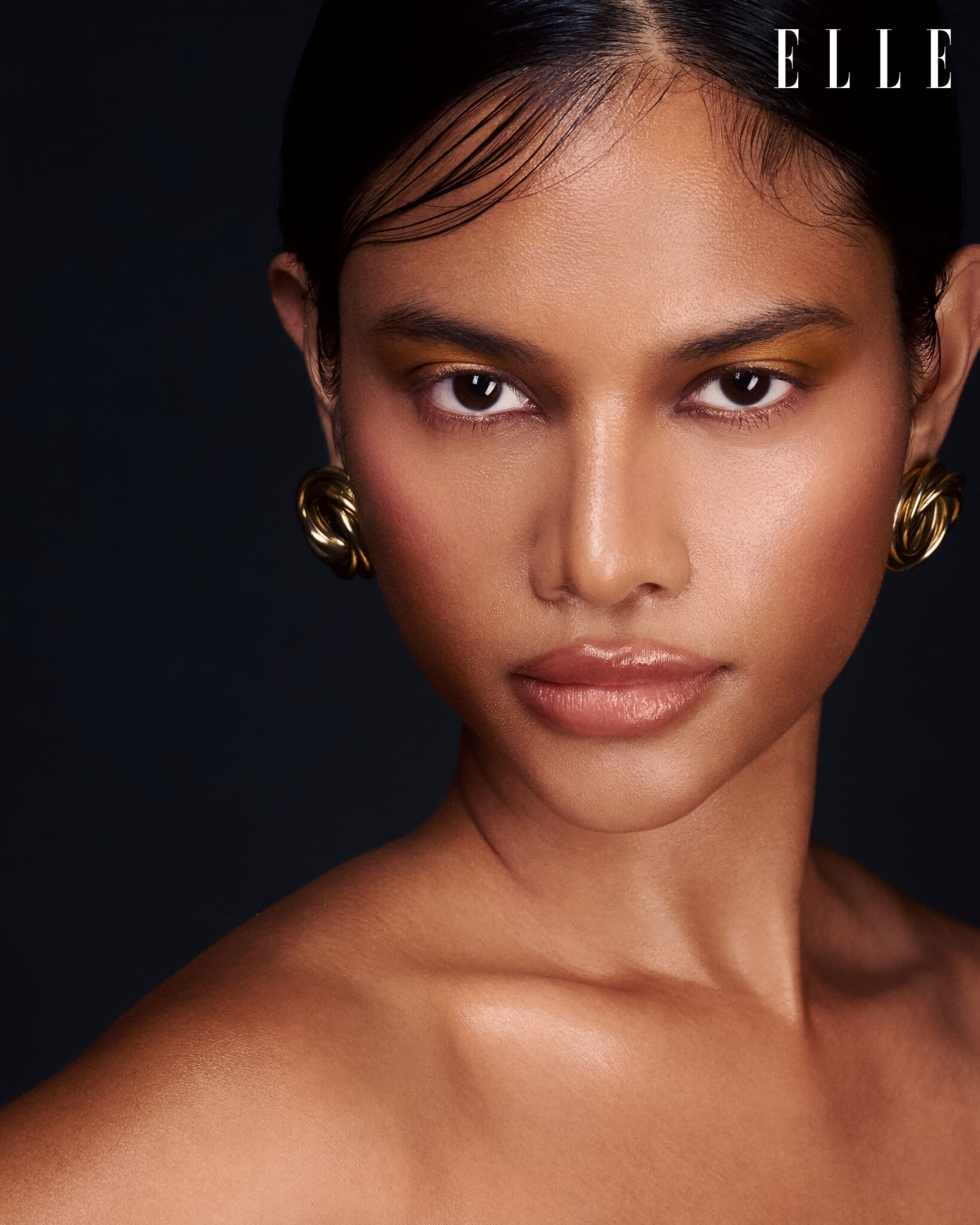 Beauty portrait with gold earrings against a dark backdrop