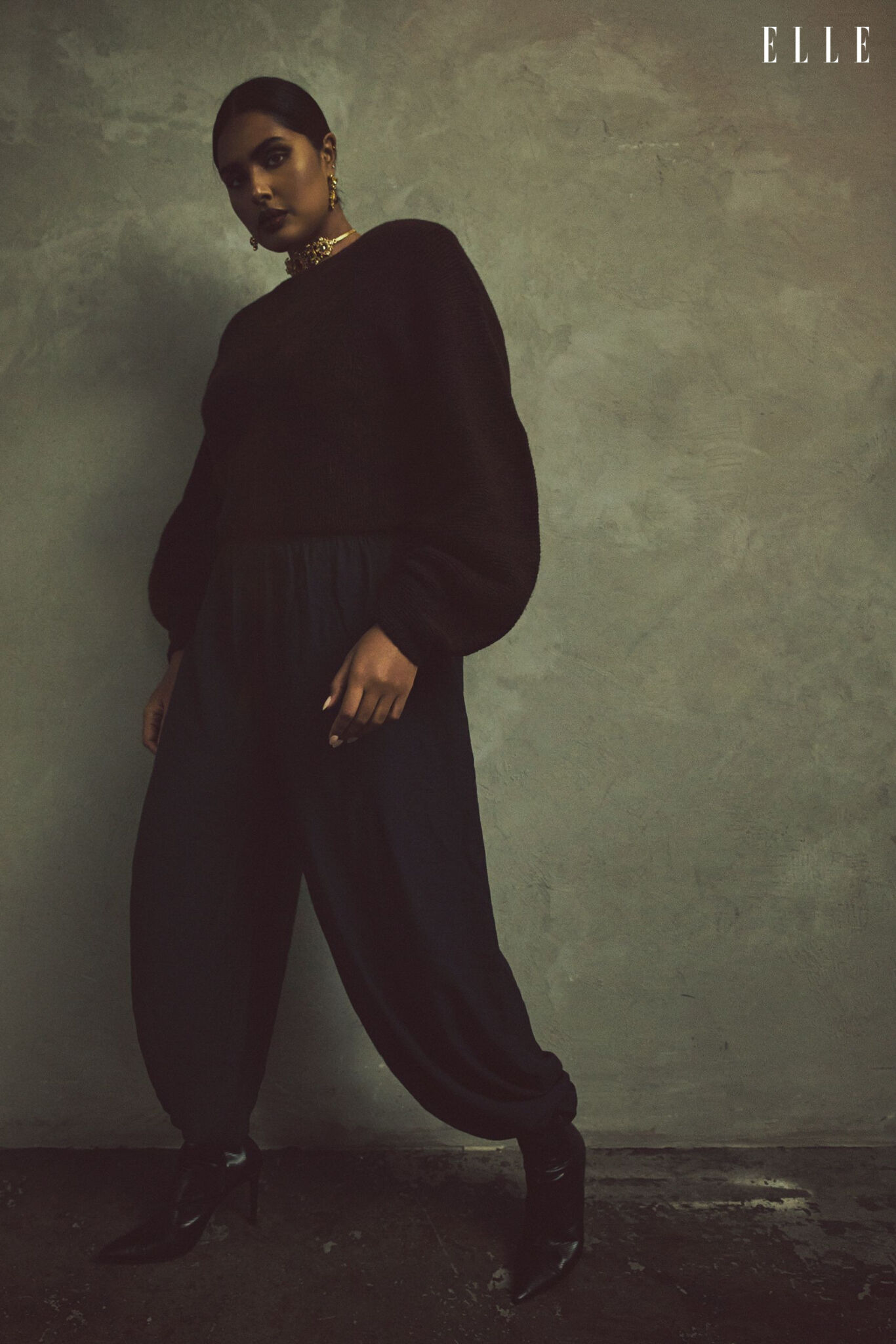 Shanaya Peters in a sculptural dark sweater, loose trousers and boots.