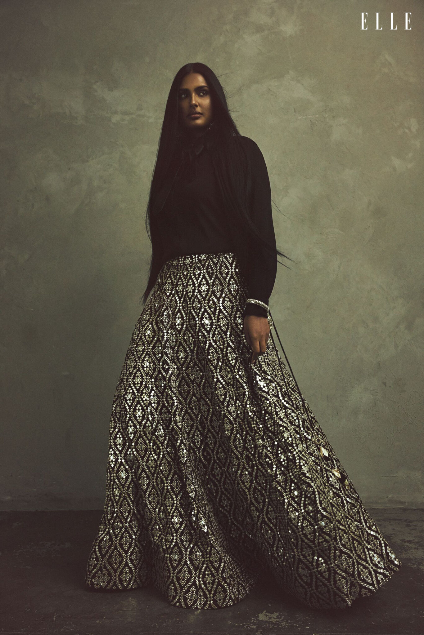 Full-length portrait of Shanaya Peters in a shirt, tie and patterned skirt.