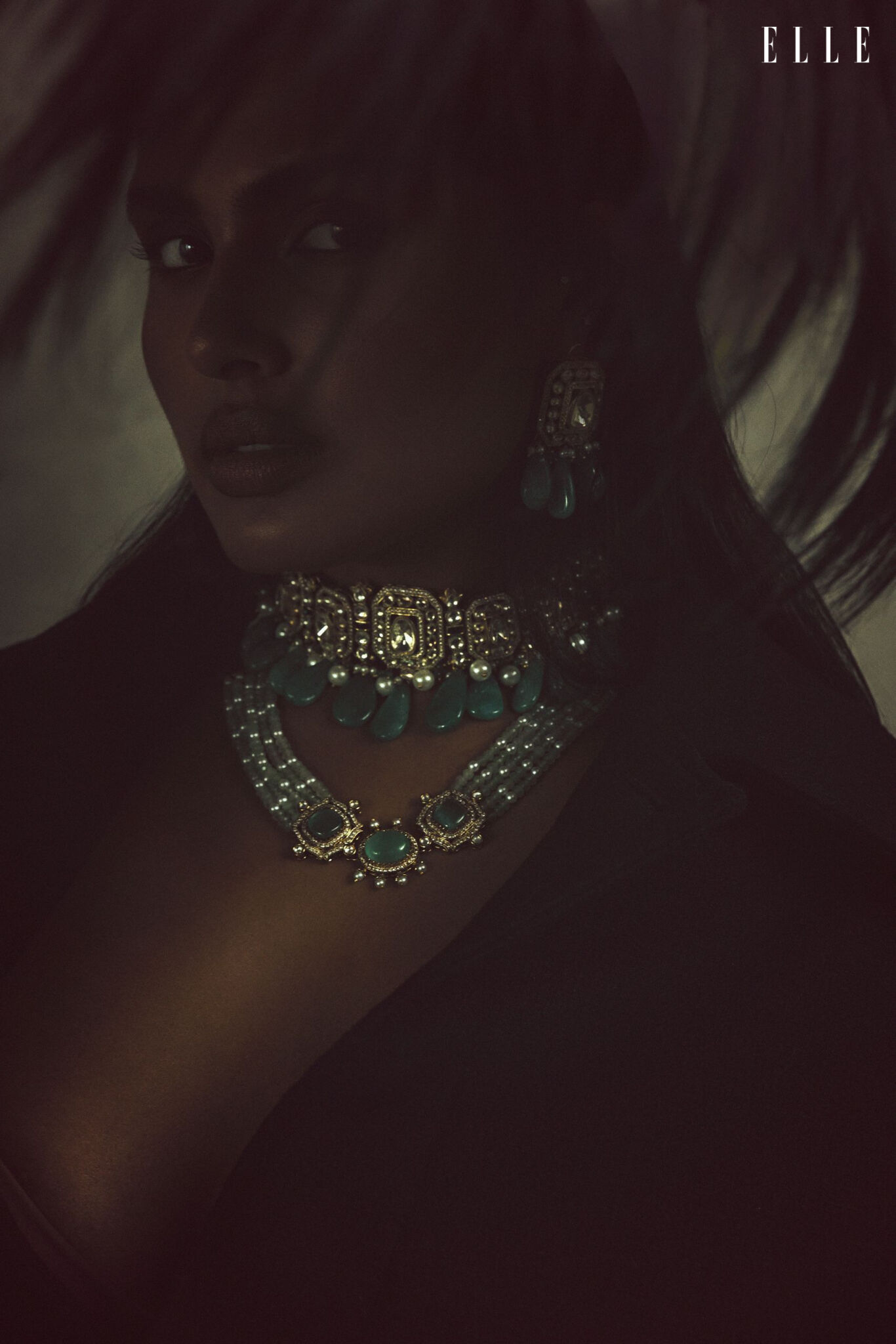 Close-up of Shanaya Peters wearing layered green-stone necklaces and earrings.