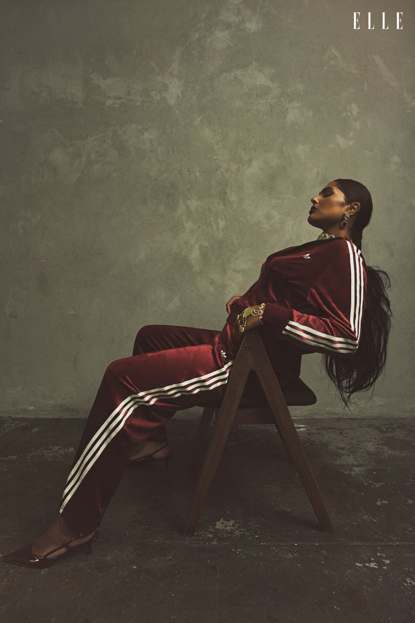 Shanaya Peters seated in a burgundy adidas tracksuit and layered jewellery.